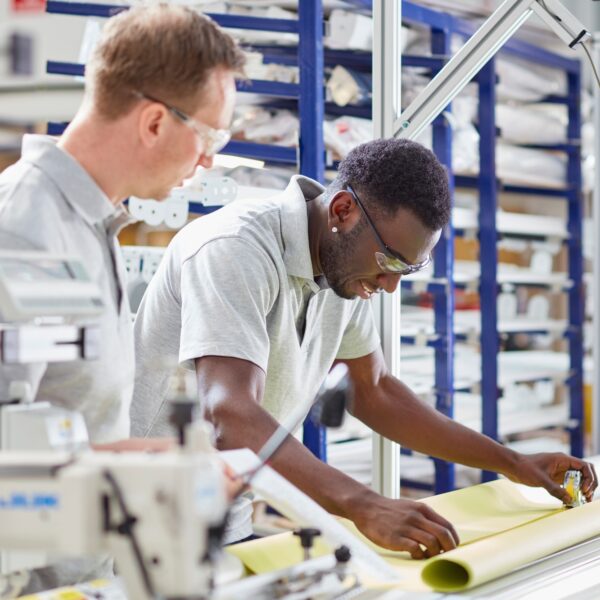 Manager mentoring worker on production line in roller blind factory